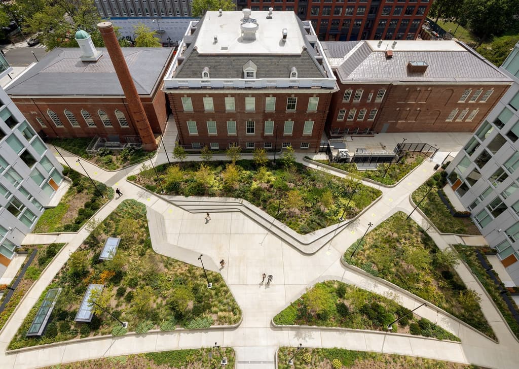 Aerial view of a courtyard with radiating paths between a historic brick building and new residential wings