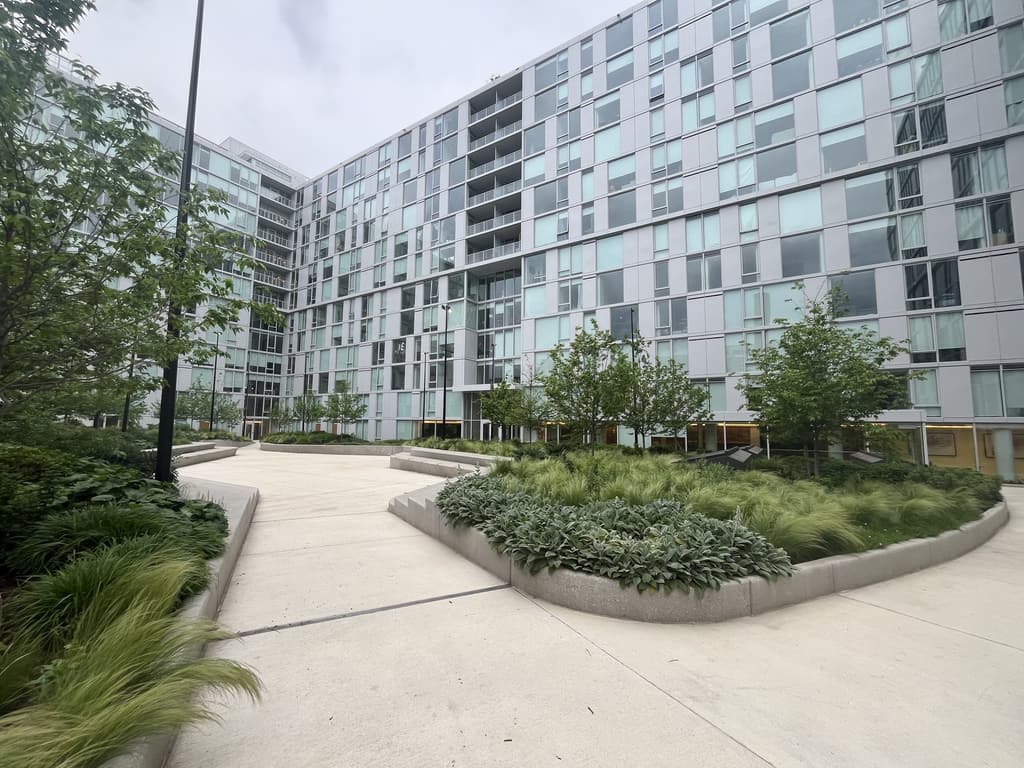 Courtyard walk curving between planted beds, with the residential wings beyond